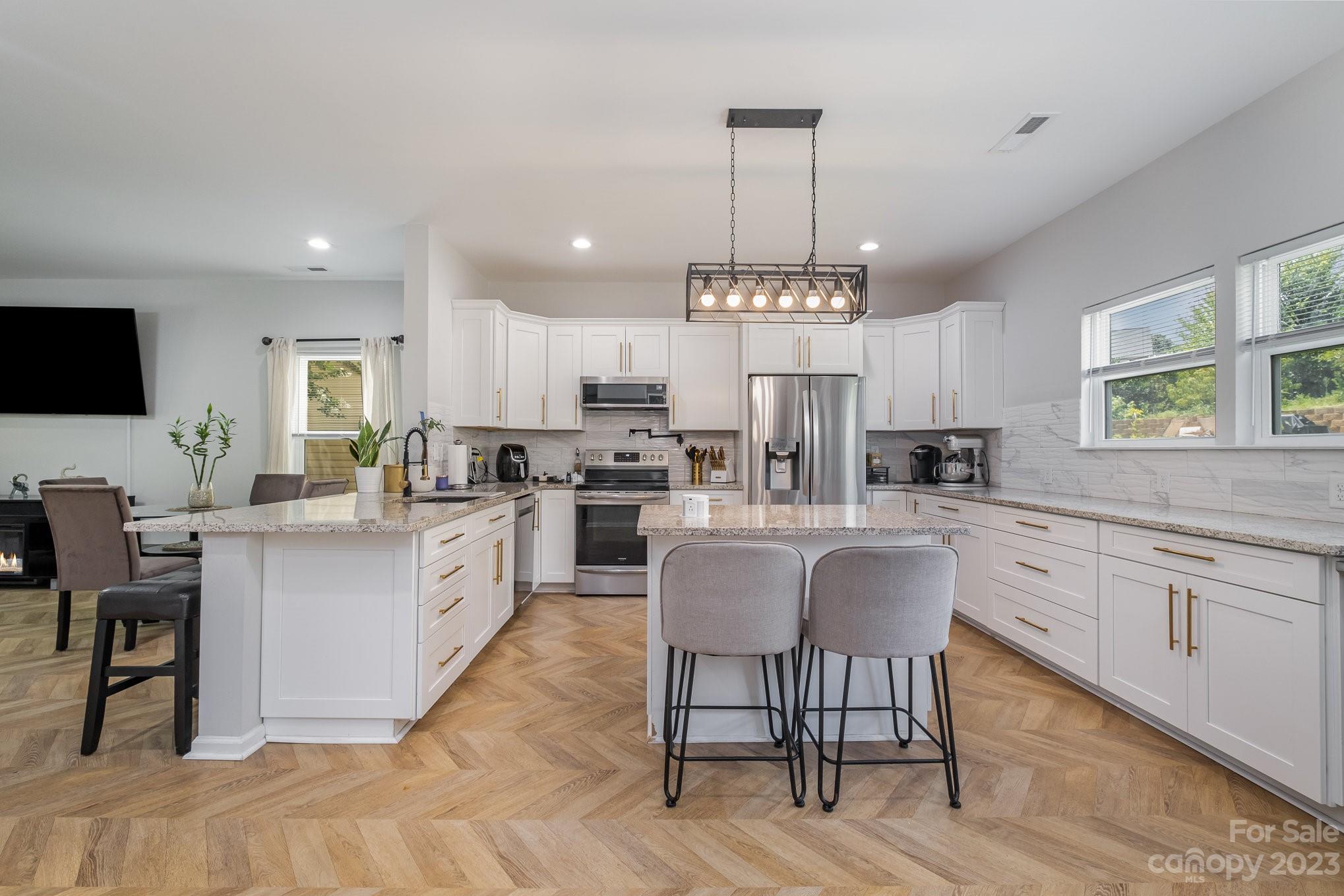 2213 Turtle Point Road Charlotte, NC 28262 - Photo 9 of 28 a large white kitchen with cabinets chairs and stainless steel appliances
