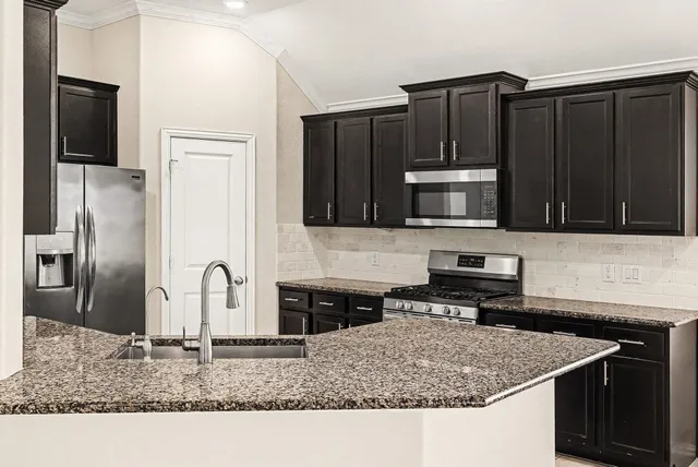 a kitchen with stainless steel appliances granite countertop a sink stove and microwave