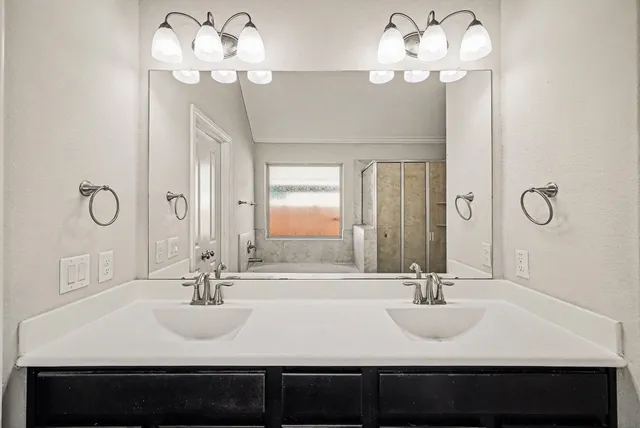 a bathroom with a sink a large mirror and a light fixture
