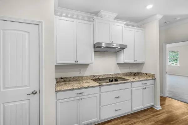 a kitchen with granite countertop white cabinets and a stove