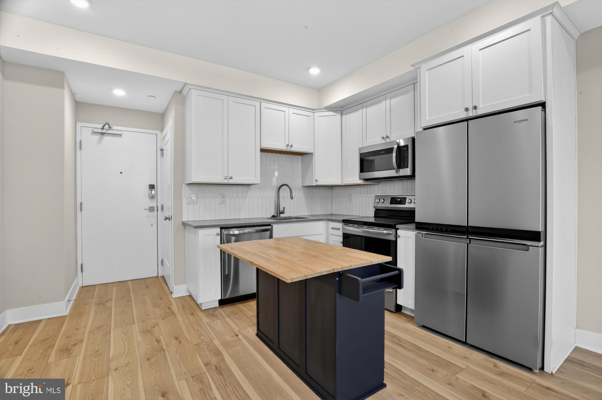 5230 Walnut Street, Unit 2F Philadelphia, PA 19139 - Photo 1 of 21 a kitchen with a refrigerator a stove top oven and white cabinets