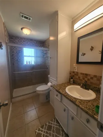 a bathroom with a granite countertop sink toilet a mirror and vanity