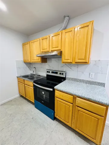 a kitchen with granite countertop wooden cabinets and a stove top oven