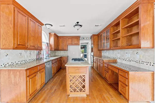 a kitchen with stainless steel appliances granite countertop a stove a sink dishwasher and cabinets with wooden floor