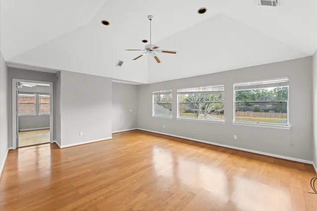 a view of an empty room with a window and a kitchen view