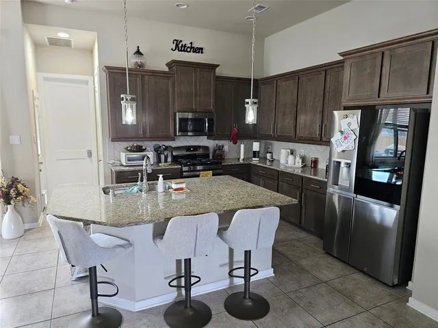 a kitchen with stainless steel appliances granite countertop a table chairs sink and cabinets