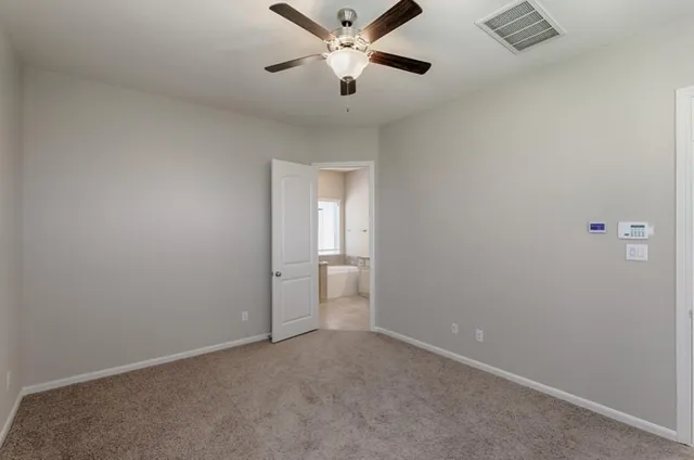 an empty room with closet and a ceiling fan