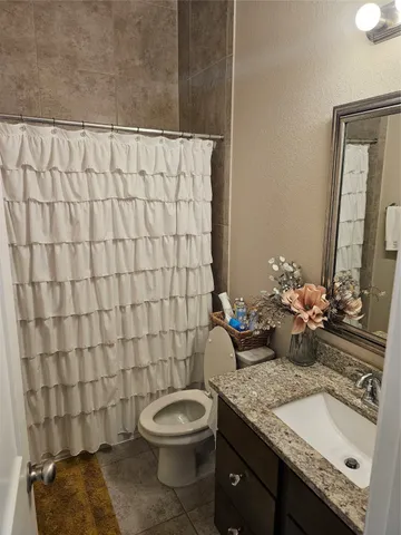a bathroom with a granite countertop sink and a toilet
