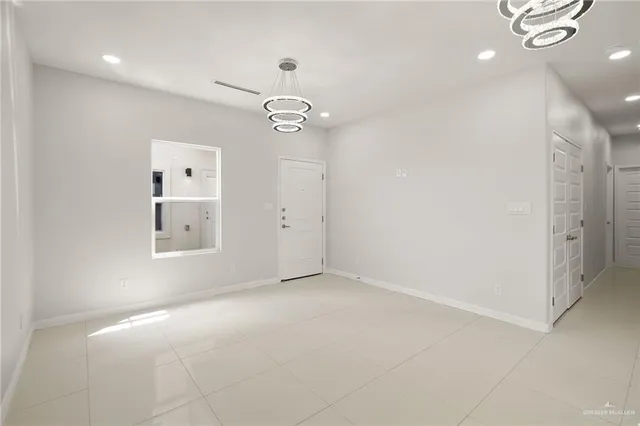 an empty room with chandelier fan and windows