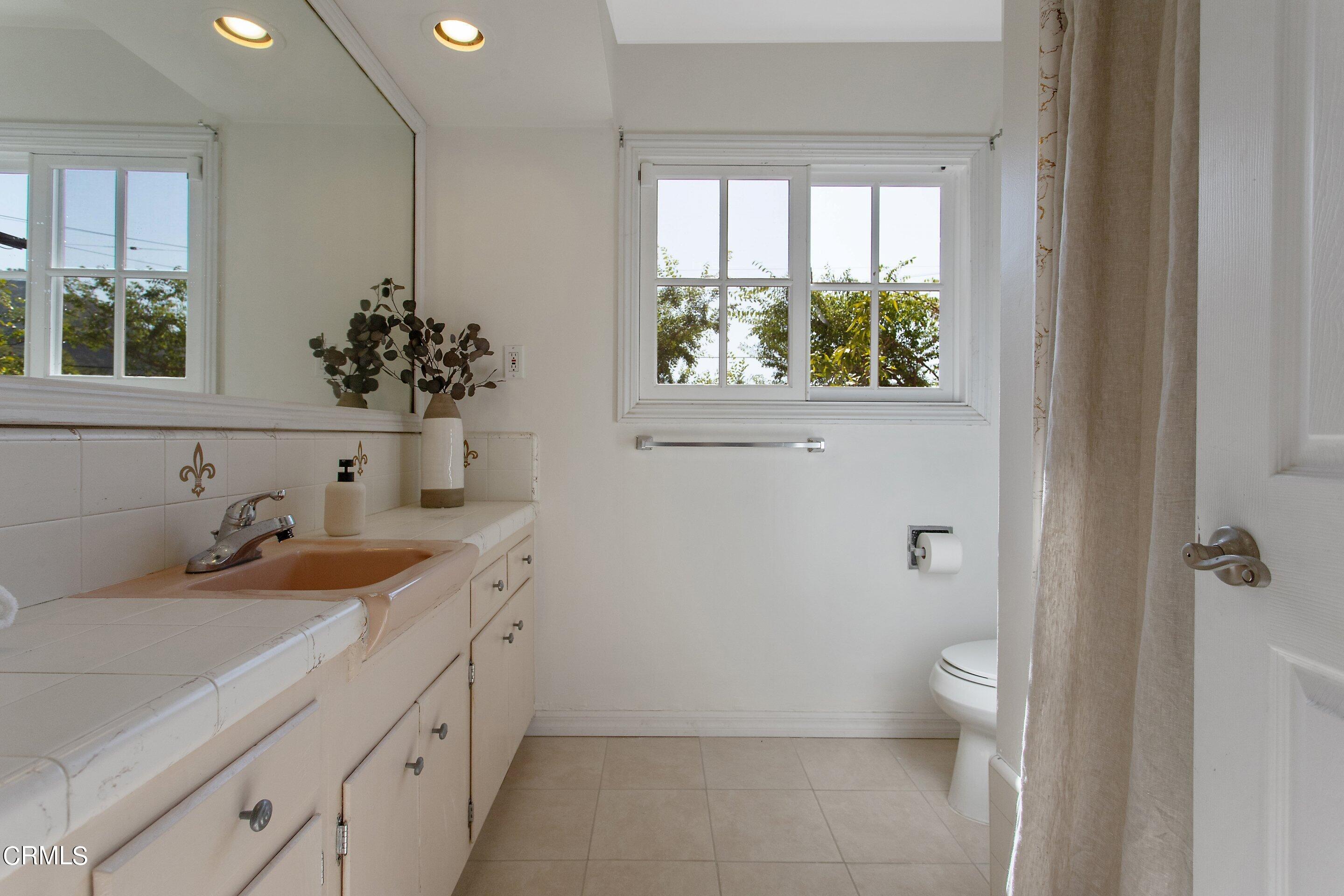3170 Buckingham Road Glendale, CA 91206 - Photo 35 of 47 a bathroom with a granite countertop sink a large mirror a toilet and a window