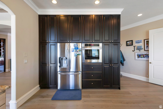 684 North Summit Way Alpine, UT 84004 - Photo 22 of 58 Kitchen featuring crown molding, stainless steel appliances, dark wood finish cabinets, light wood-style floors, and arched walkways