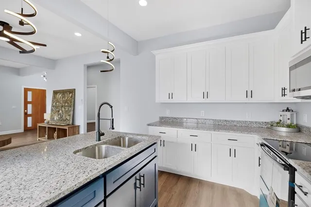 a kitchen with granite countertop a sink a stove and cabinets