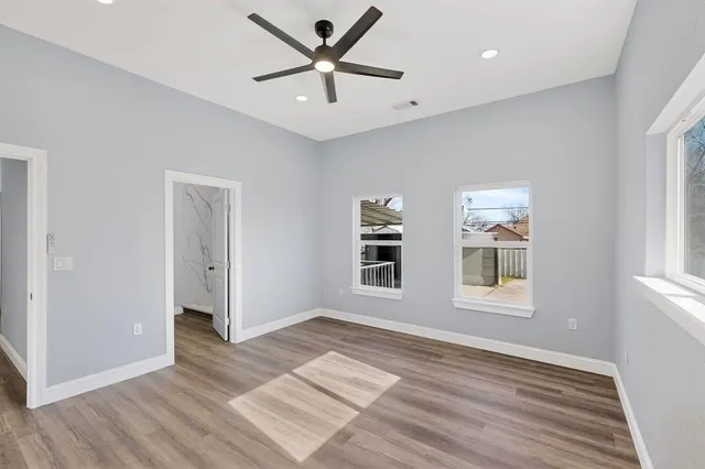 a view of an empty room with a window and wooden floor