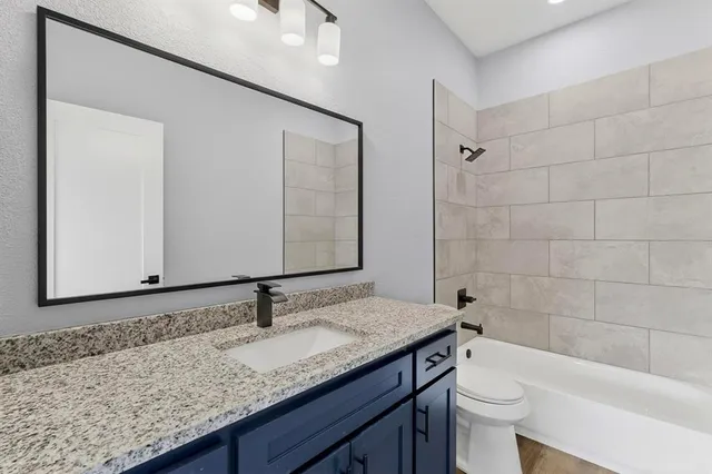 a bathroom with a granite countertop sink a toilet and bathtub