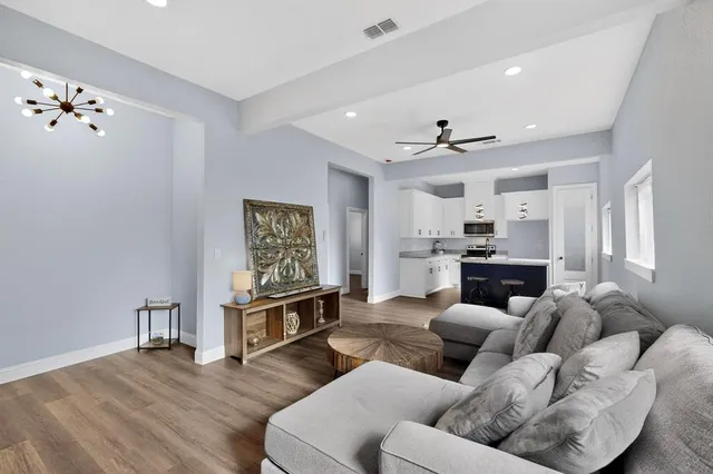 a living room with furniture kitchen view and a chandelier