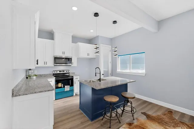 a kitchen with granite countertop kitchen island stainless steel appliances a sink stove and refrigerator