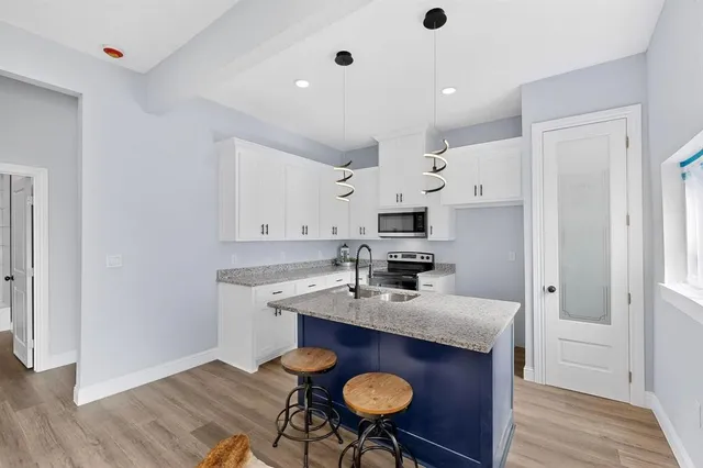 a kitchen with kitchen island granite countertop a sink cabinets and wooden floor