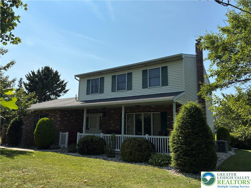 A classic brick and siding two-story home presents a welcoming front porch and well-kept landscaping.