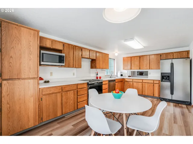 a kitchen with stainless steel appliances granite countertop a refrigerator a stove a sink dishwasher and white countertops with wooden floor