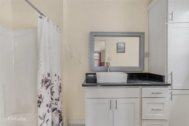 a bathroom with a granite countertop sink a mirror and shower