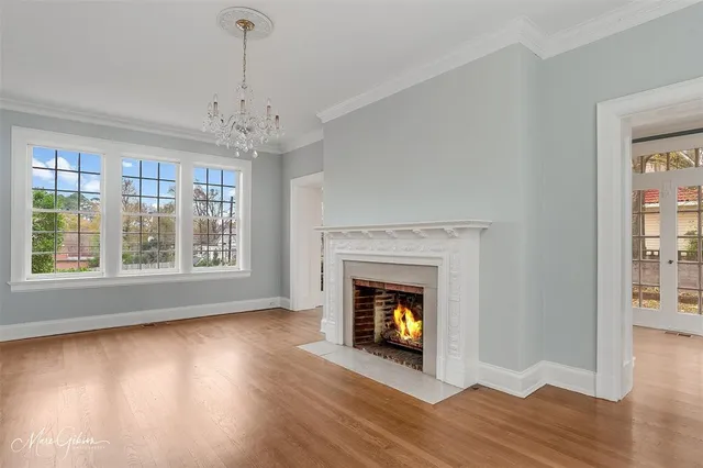 a view of an empty room with wooden floor fireplace and a window