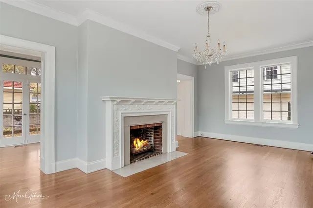 a view of an empty room with wooden floor fireplace and a window