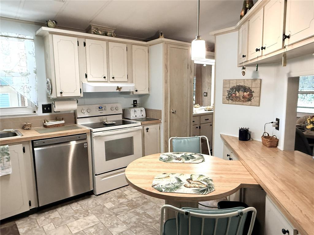 4418 Brave Lane St. Cloud, FL 34772 - Photo 11 of 29 a kitchen with stainless steel appliances kitchen island granite countertop a sink a stove a refrigerator and white cabinets