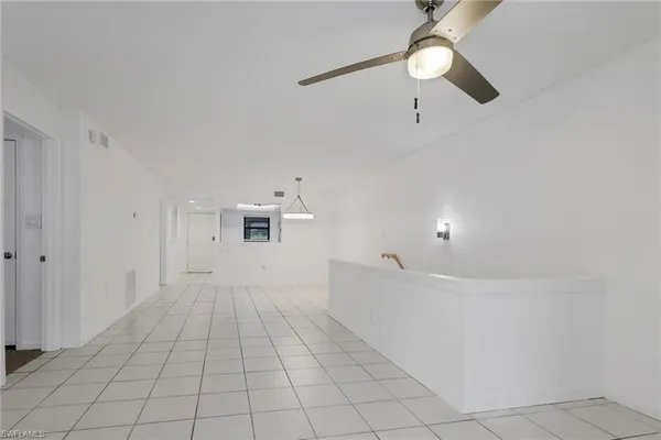 a view of an empty room with window and chandelier fan