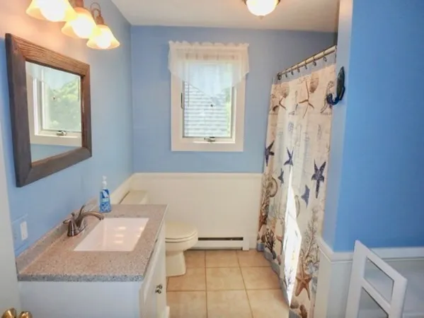 a bathroom with a granite countertop sink a toilet and shower