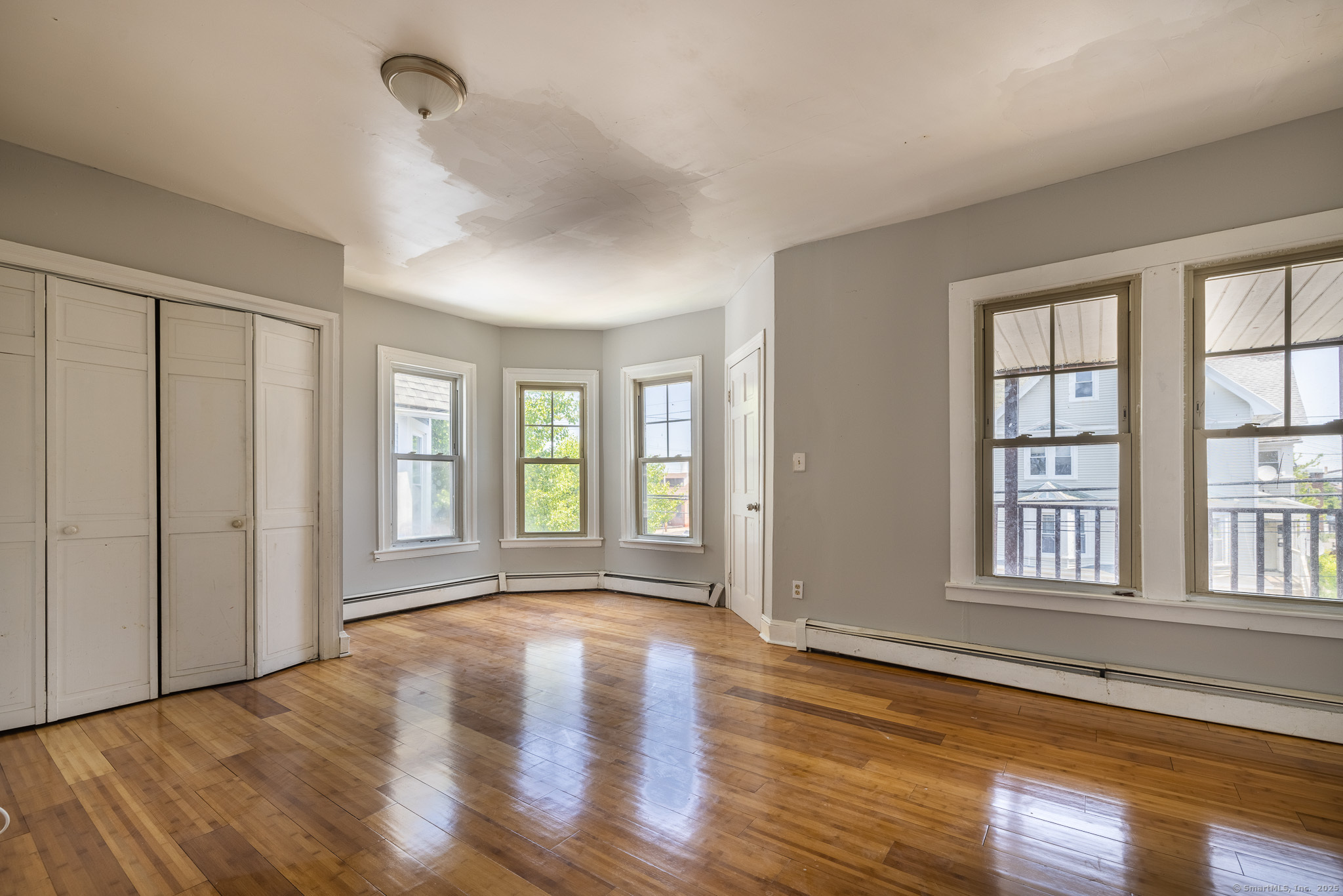a view of an empty room with wooden floor and a window