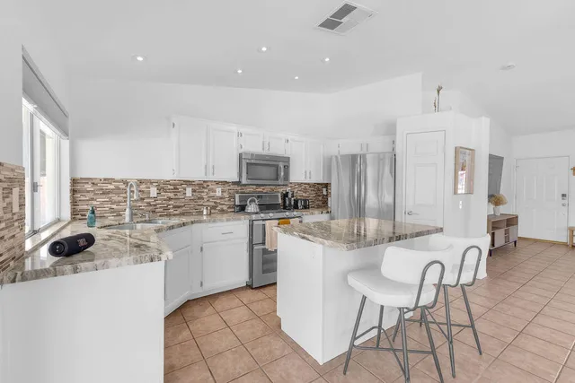 a kitchen with granite countertop a refrigerator and a stove top oven