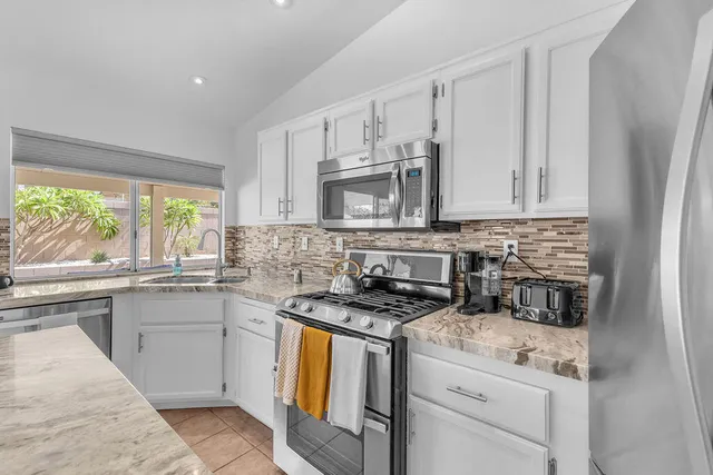 a kitchen with granite countertop white cabinets and a window