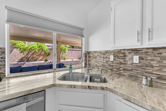 a kitchen with stainless steel appliances granite countertop a refrigerator a stove a sink dishwasher and white cabinets with wooden floor