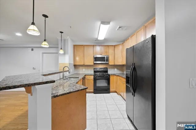 a kitchen with granite countertop stainless steel appliances a refrigerator a sink a stove cabinets and living room view