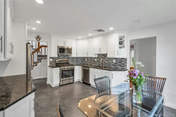 a kitchen with granite countertop stainless steel appliances a sink and a refrigerator