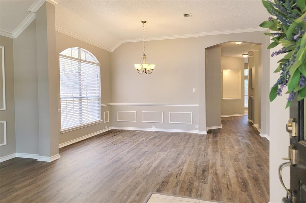 1604 Knoll Ridge Circle Corinth, TX 76210 - Photo 6 of 37 Spacious room featuring wood-finish flooring, a large arched window with blinds, and decorative wall paneling