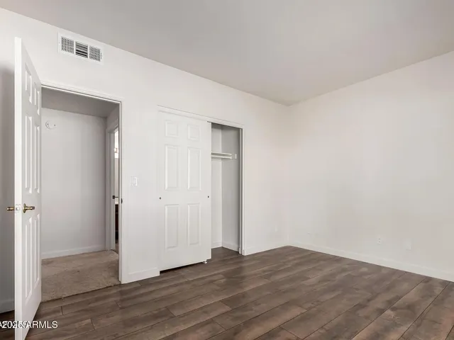 a view of an empty room with wooden floor and closet