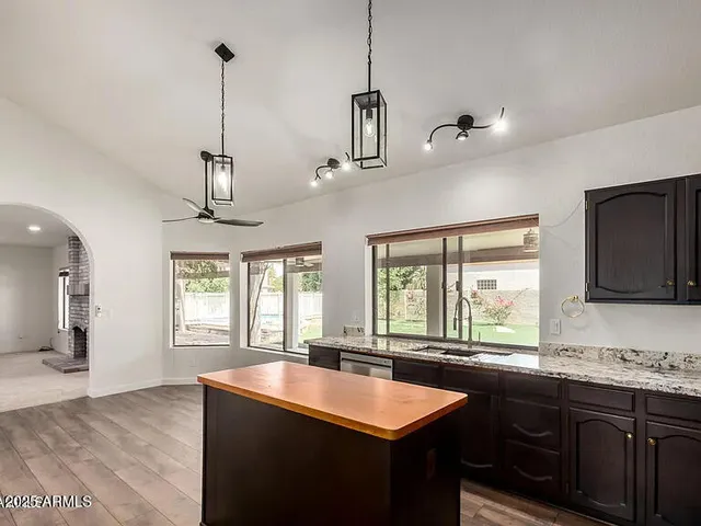 a kitchen with stainless steel appliances granite countertop a sink a window and chairs