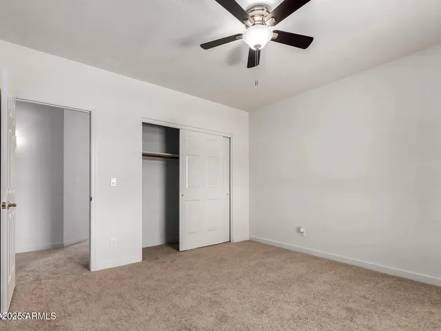 an empty room with closet and a ceiling fan