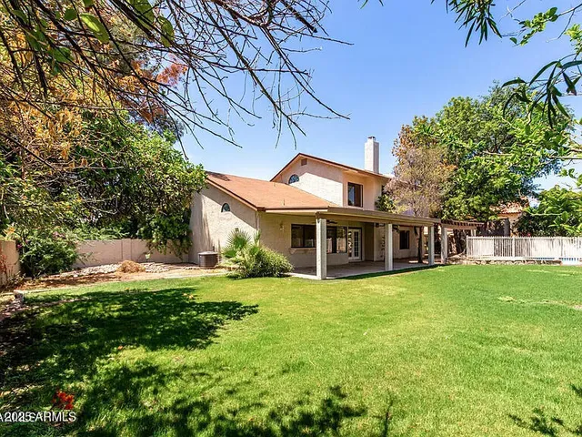 a view of a house with a big yard and large trees