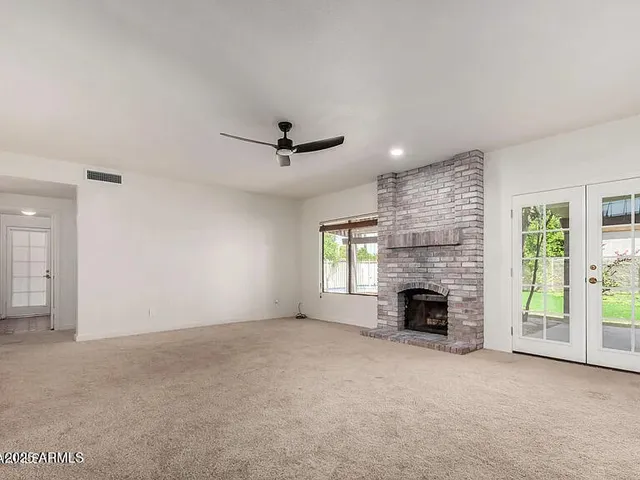 an empty room with windows and fireplace