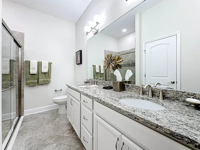 a bathroom with a granite countertop sink mirror and toilet