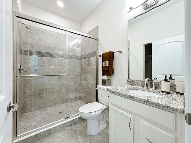 a bathroom with a granite countertop sink toilet a mirror and shower