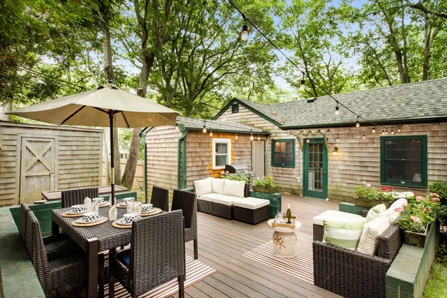 a view of a patio with couches table and chairs under an umbrella