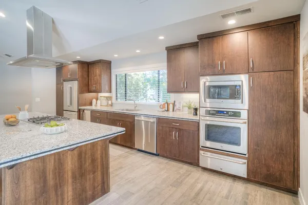 a large kitchen with kitchen island a stove a sink a dining table and chairs