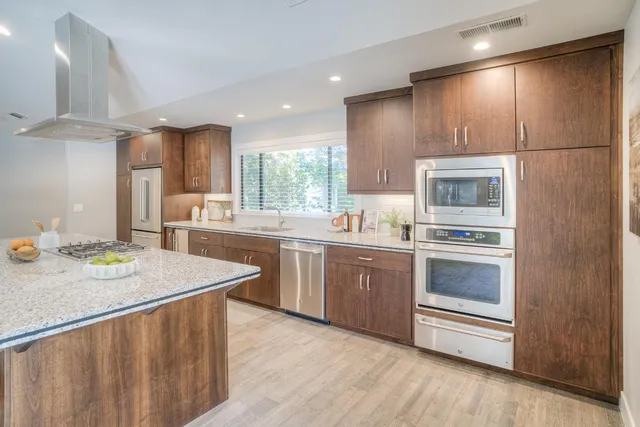 a large kitchen with kitchen island a stove a sink a dining table and chairs