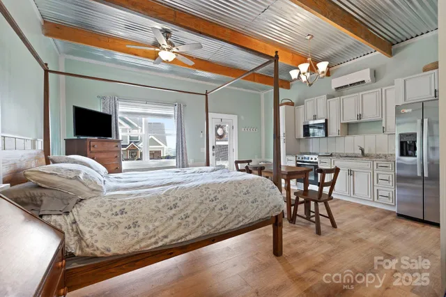 a bedroom with a bed a chandelier and flat screen tv