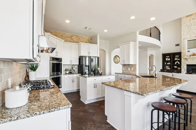 a kitchen with stainless steel appliances granite countertop a stove top oven a sink dishwasher and white cabinets