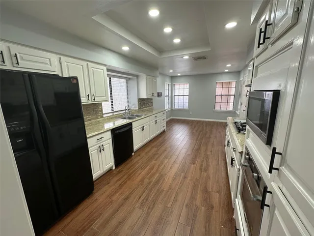 a kitchen with granite countertop a refrigerator stove and wooden floor