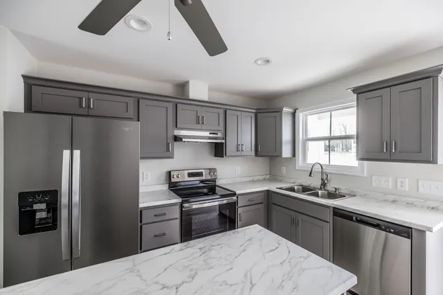 a kitchen with stainless steel appliances granite countertop a refrigerator stove top oven and sink